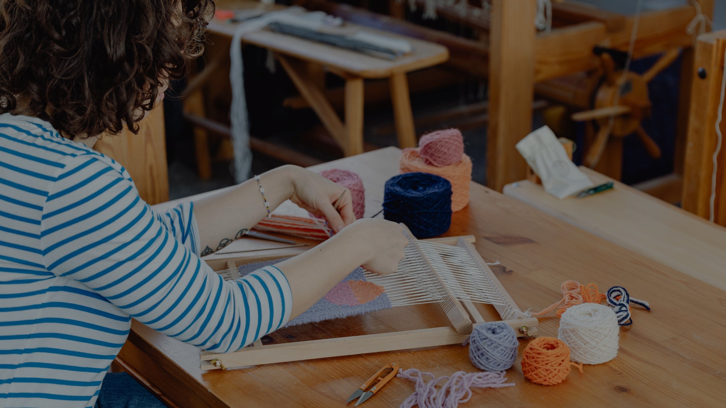 Person working with yarn and a loom in a workshop setting